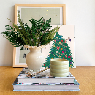 Classic Winter dried flower arrangement in forest green and frosted pods in a gloss milk-glass ruffle vase